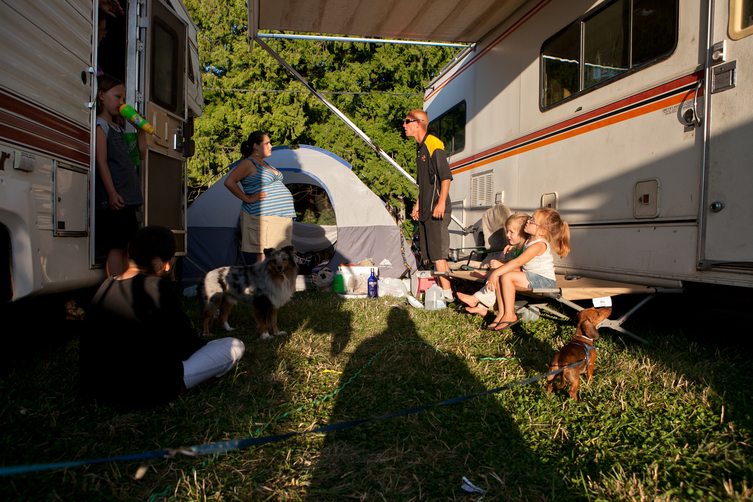 Carnival workers oftentimes travel with their families. Therefore, living and working quarters are rarely separated. In the carnival camp, two recreational vehicles are parked within close proximity to each another. A husband and wife argue while children play near them.