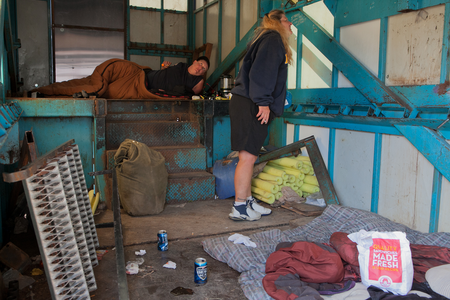  Two carnival workers awake and rise. This is the belly of the tractor-trailer that transports the Merry-Go-Round. After rides are erected, workers oftentimes use the trailers as shelter. 