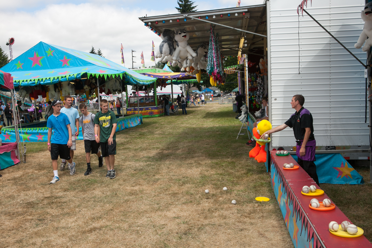 Carnival workers are trained to “bark.” Barking involves having a phrase or action that entices passers-by to acknowledge the game and worker. Here, a game operator strategically knocked over some balls and asked the boys to help pick them up. As the boys come closer, the carnival worker will engage them and entice them to play, thus getting them to spend money.