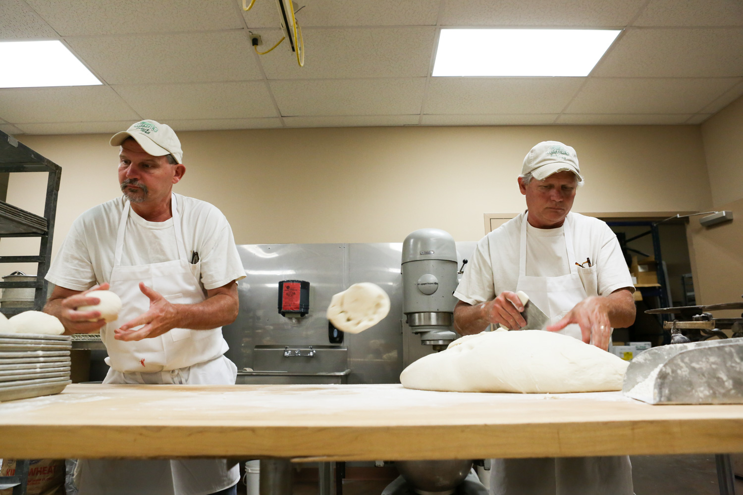  At their family bakery, Paul (right) tosses a piece of dough (used for donuts) to his brother Joe. Each night they prepare about 300 pounds of dough for their signature donuts, in addition to pastries, breads, cakes and others goods. 