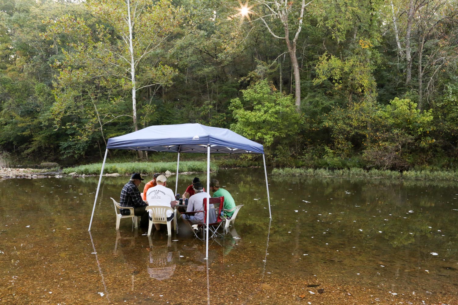  In a shallow creek on their farm, Paul and Joe join a group of friends and co-workers. During warmer months, they set up a table and canopy in the water to play cards and keep cool. 