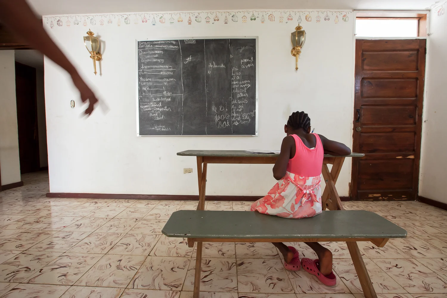 Children from a nearby orphanage also attend school regularly in Gramothe. On a day off from classes, a girl reviews lessons in the orphanage's common room.