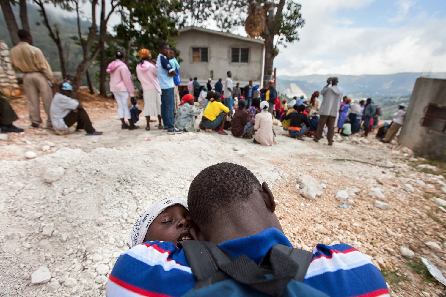Two boys sleep on one another as they await their turn with a nurse at Gramothe's medical clinic. The teen carried his younger sibling for hours on foot to seek treatment. Medical teams from outside Haiti provide care to villagers several times a year.