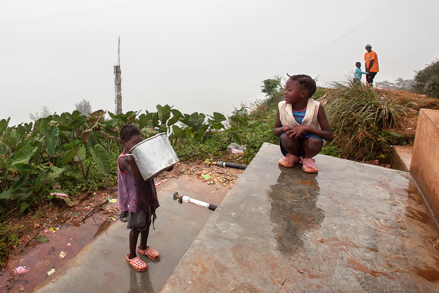  Family members take turns collecting mountain spring water from a newly installed spigot for daily cooking, bathing, drinking, and laundering. 