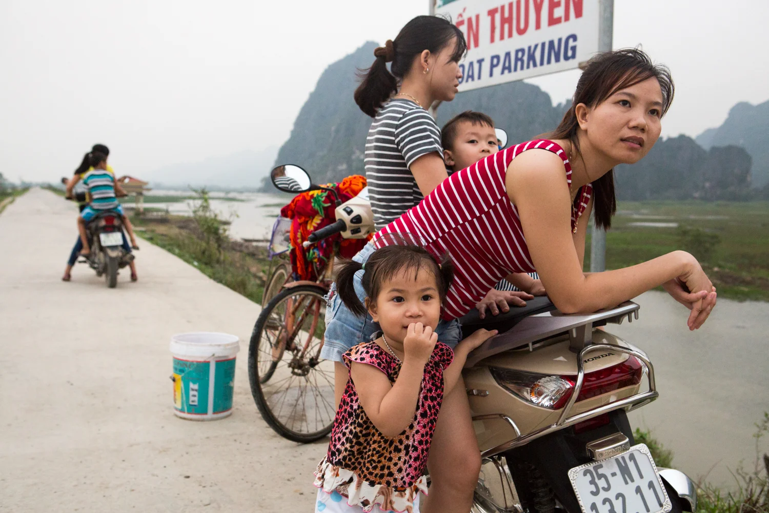 At Van Long, in Vietnam's Ninh Binh province, a family gathers on their motorbike and observes the rugged landscape.