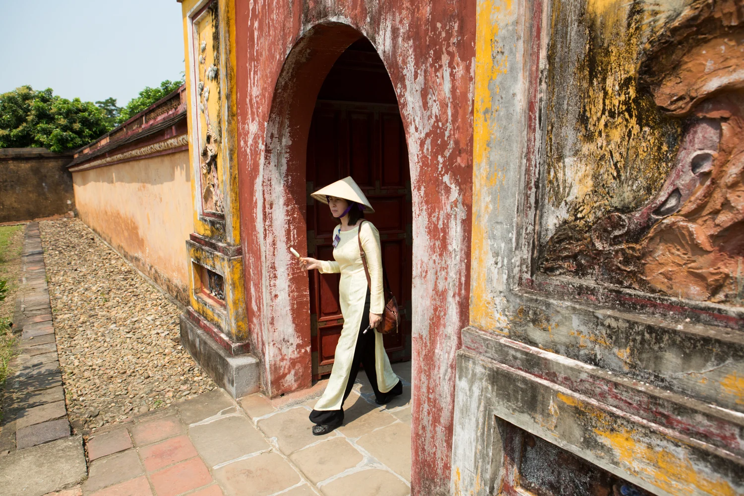 A Vietnamese tour guide eats ice cream as she walks through The Citadel - The Royal Palace - in Hue, Vietnam.