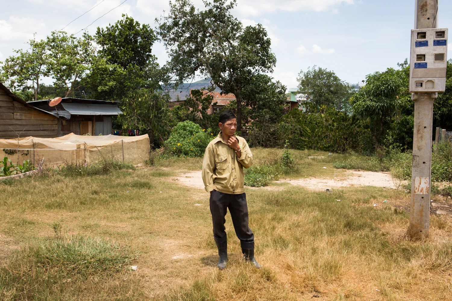 In a small village on the outskirts of Dalat, a man stands in a vacant housing lot.