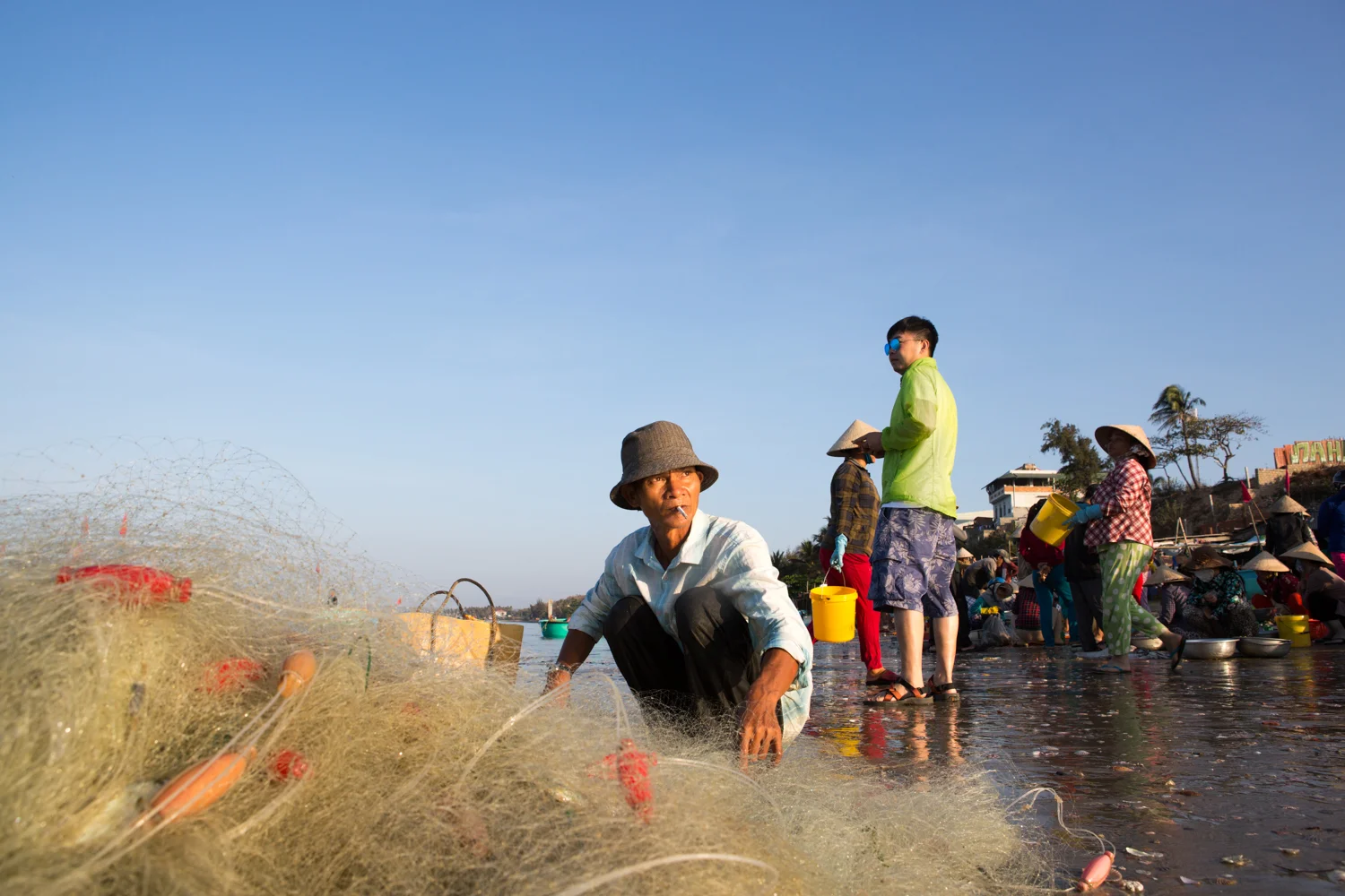 On the beach of Mui Ne, Vietnam, a man untangles his fishing net to collect his daily catch.