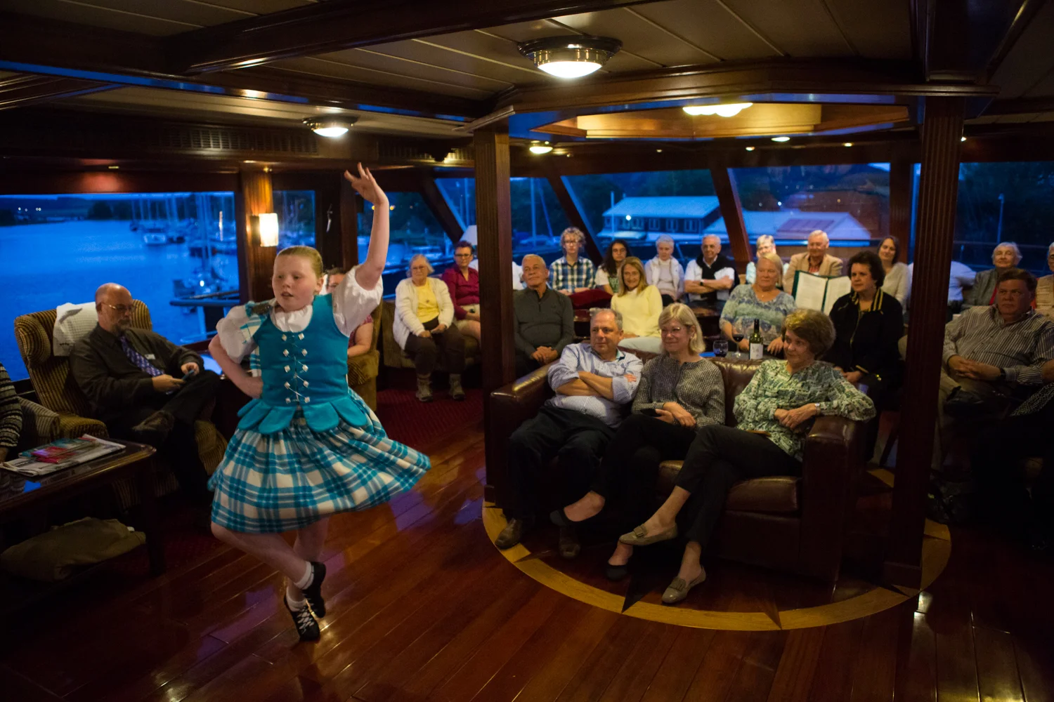Aboard the Lord of the Glens Expedition Vessel, a young Scottish Highland Dancer performs for a group of travelers visiting Scotland.