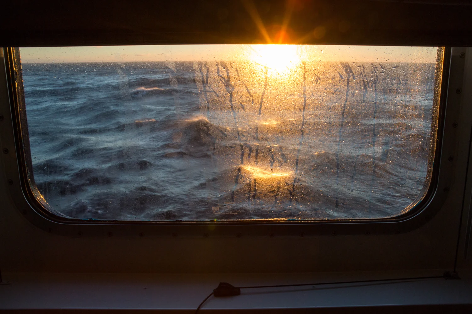 En route to L'Anse aux Meadows on board the National Geographic Explorer, the sun bursts above the horizon and into the cabin window.