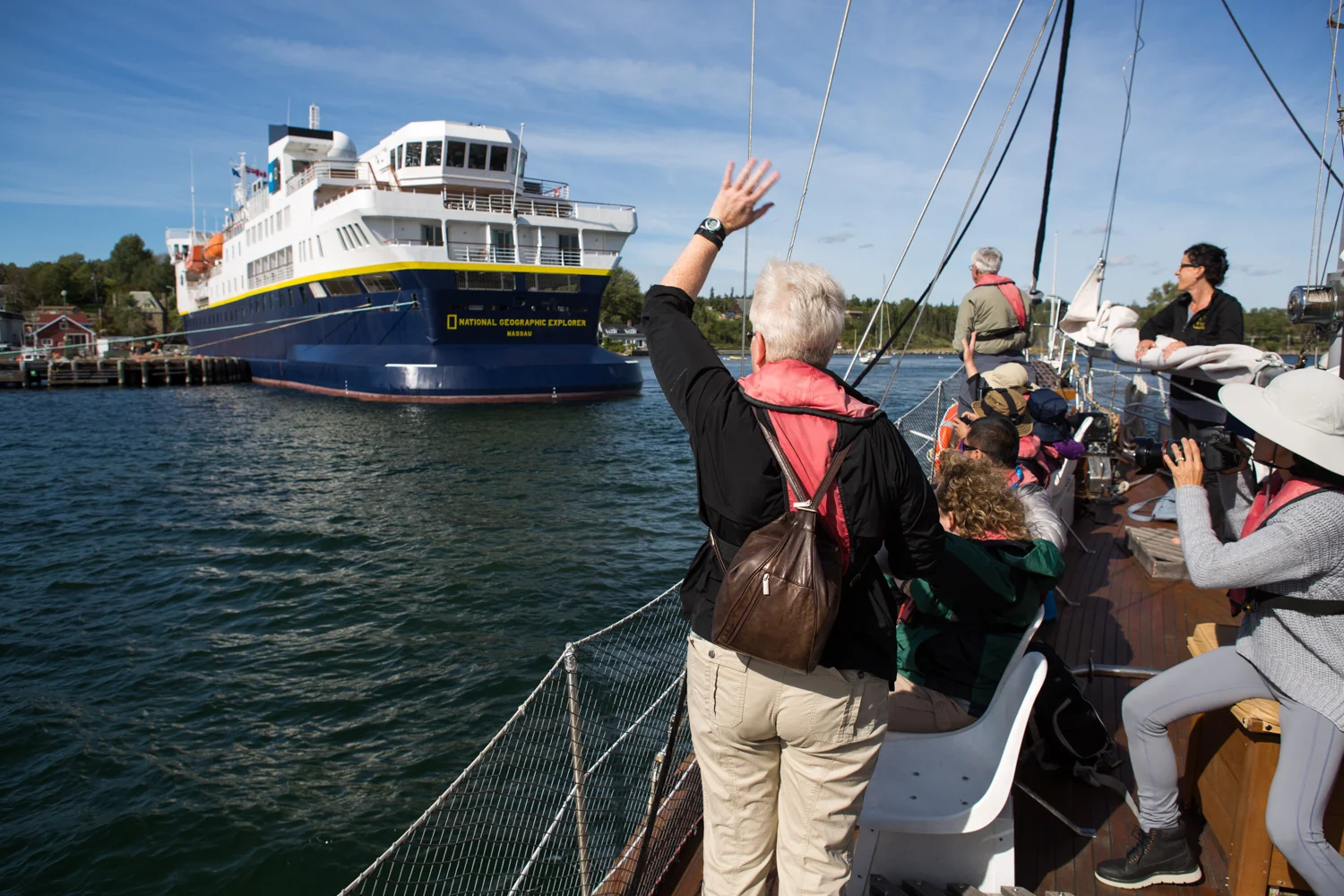 In Baddeck, Nova Scotia, a traveler aboard a schooner waves back to the National Geographic Explorer expedition vessel.