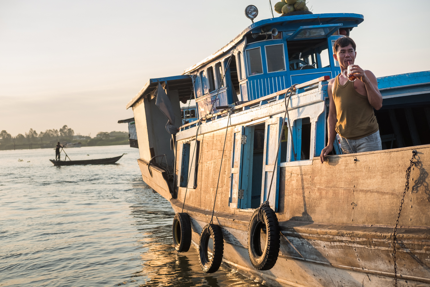  At the floating village in Chau Doc, Vietnam, boats gather in the Bassac River to buy/sell produce and fish. Here, a vendor pauses for an early morning drink. 