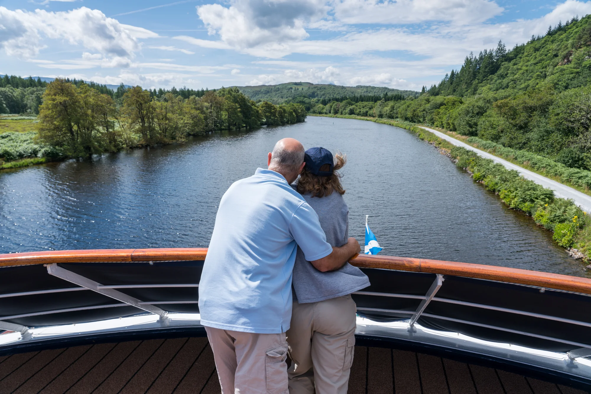 A couple shares a moment while enjoying the view and scenery along The Caledonian Canal from the bow of Lord of the Glens.
