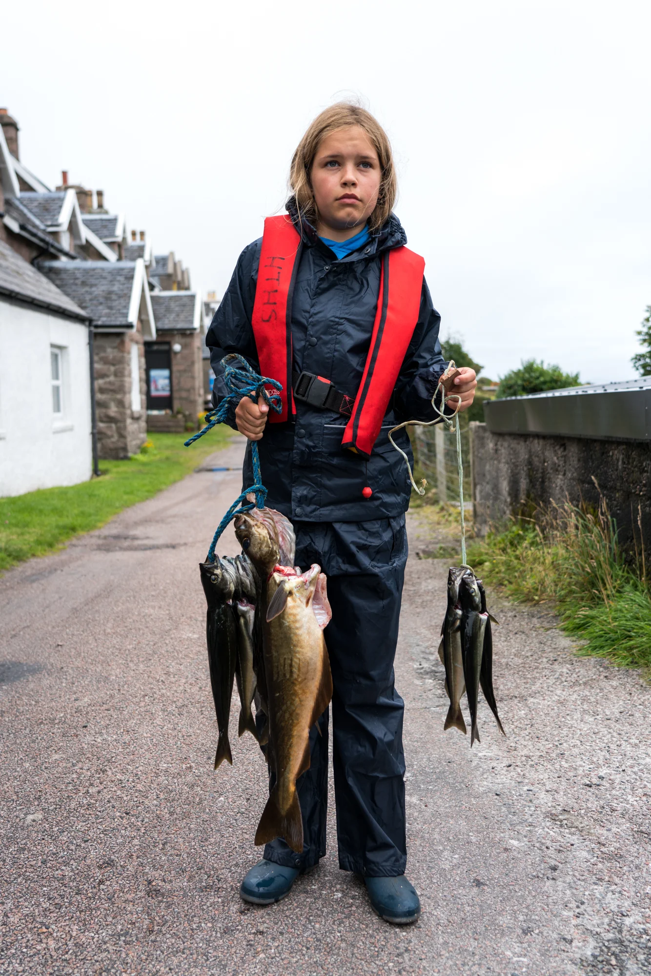 On Iona, Scotland, a young girl poses for a portrait while displaying her local daily catch.