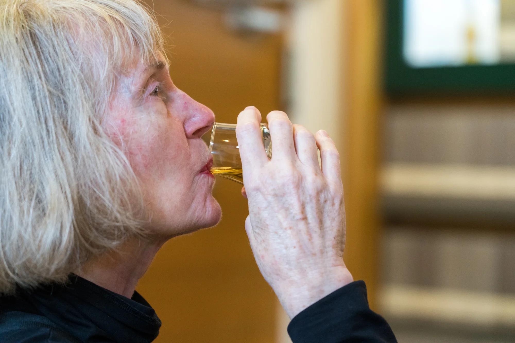 A woman samples Oban Whisky in the distillery tasting room.