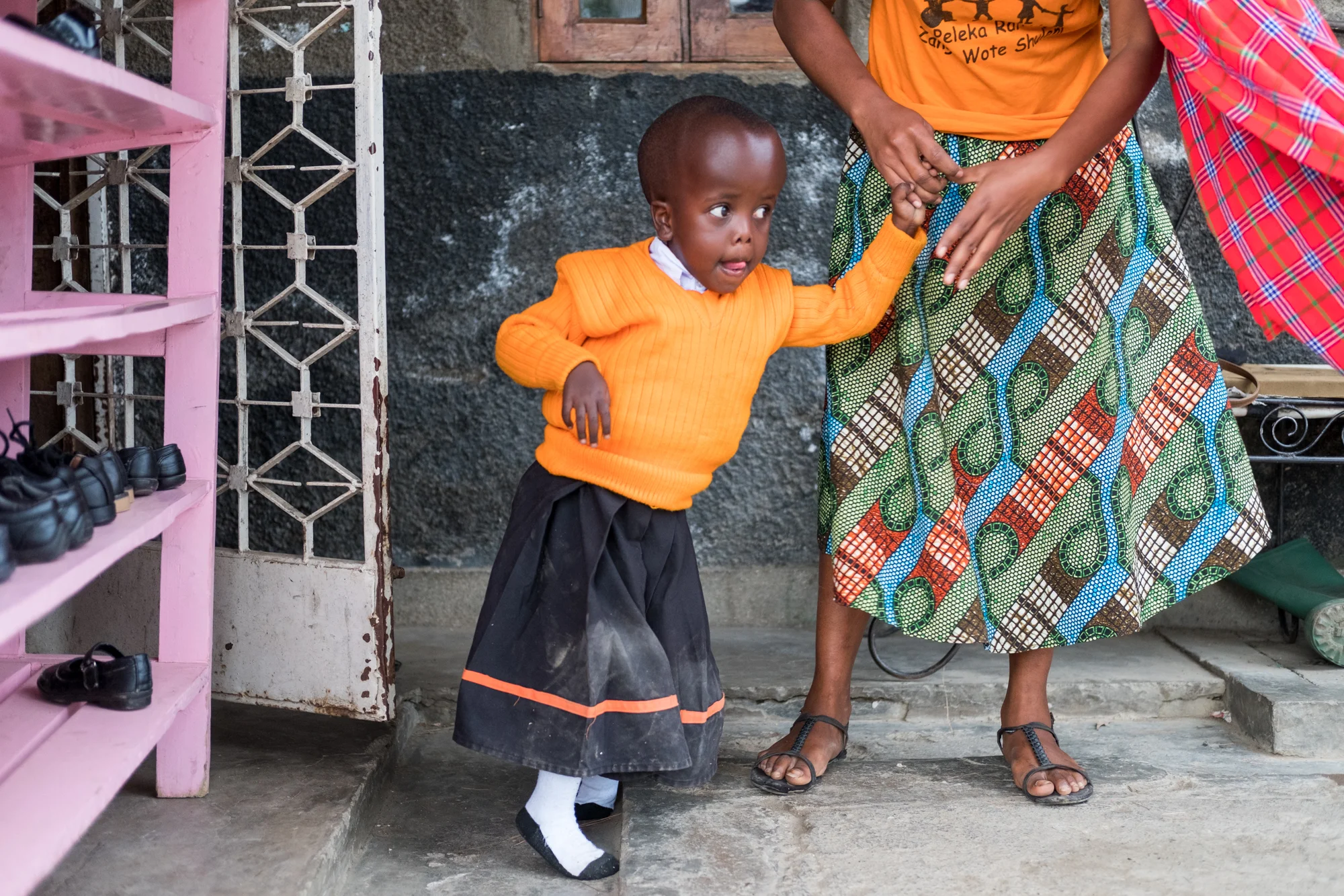 A teacher helps a student (Felistar Sabbi Mwangolela) stand up and walk at Child Support Tanzania, a non-governmental organization located in Mbeya, Tanzania, that educates disabled children.