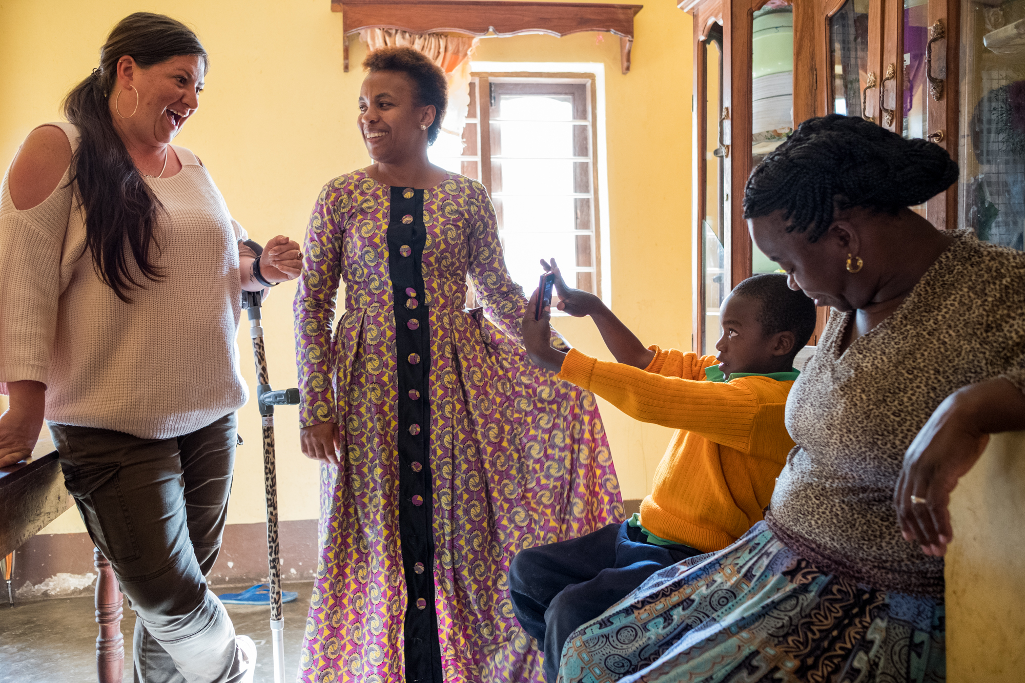  Holly visits the home of Child Support Tanzania student Edgar Philipo Mwalukisa (center-right). Edgar’s mother (right) and CST Executive Director Noelah Msuya (center-left) join them nearby. 