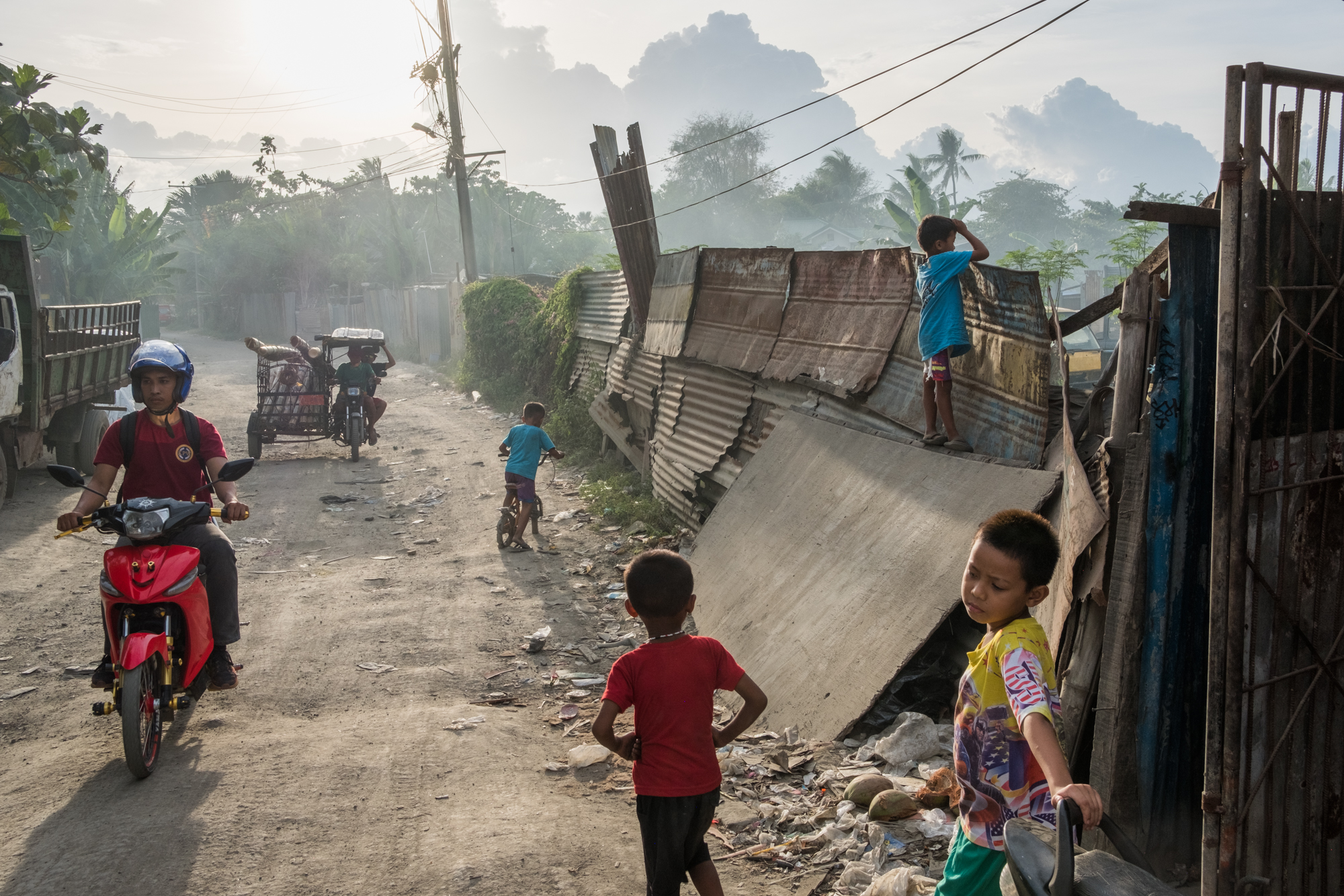  Children play as traffic goes by on a street near the Mandaue Dump Site in Cebu City, Philippines. Children usually skip school so they can work in the dumpsite to collect recyclable material, oftentimes the family’s main source of income. 