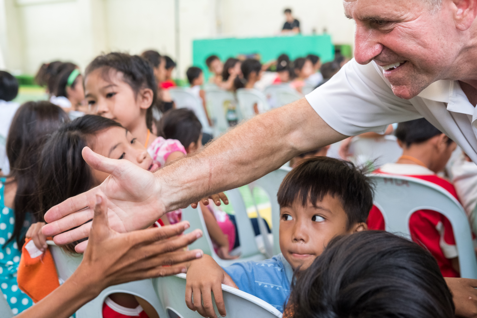  Frank Becker (right) greets children attending a community-giving event in Cebu, Philippines. During the event, Frank and local organizations include fun activities and games for the children. 