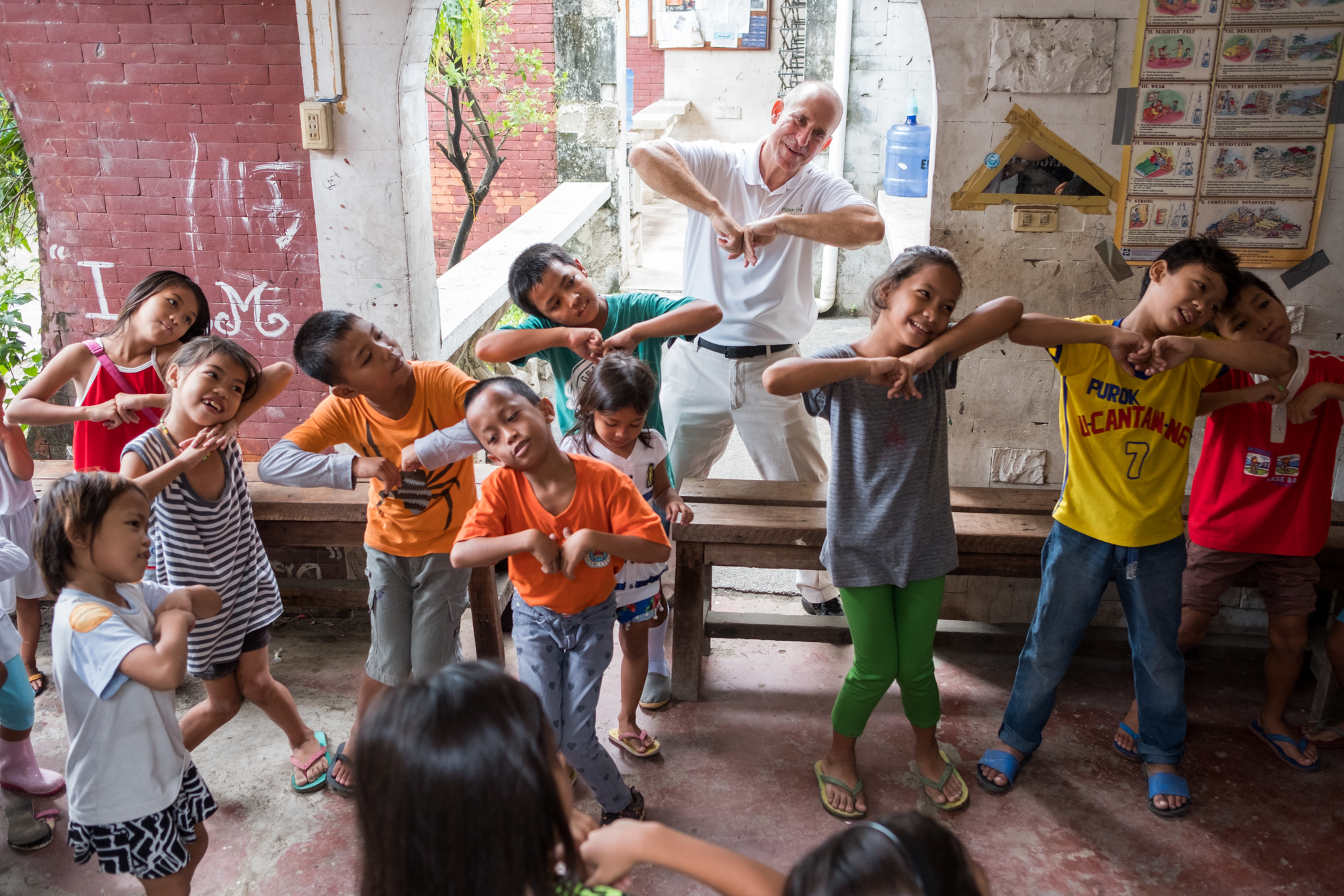  Frank Becker (back, center) dances with children during bible school at Living Bread Ministry in Cebu, Philippines. Frank instills faith-based exercises during the programs before offering school supplies and meals. 