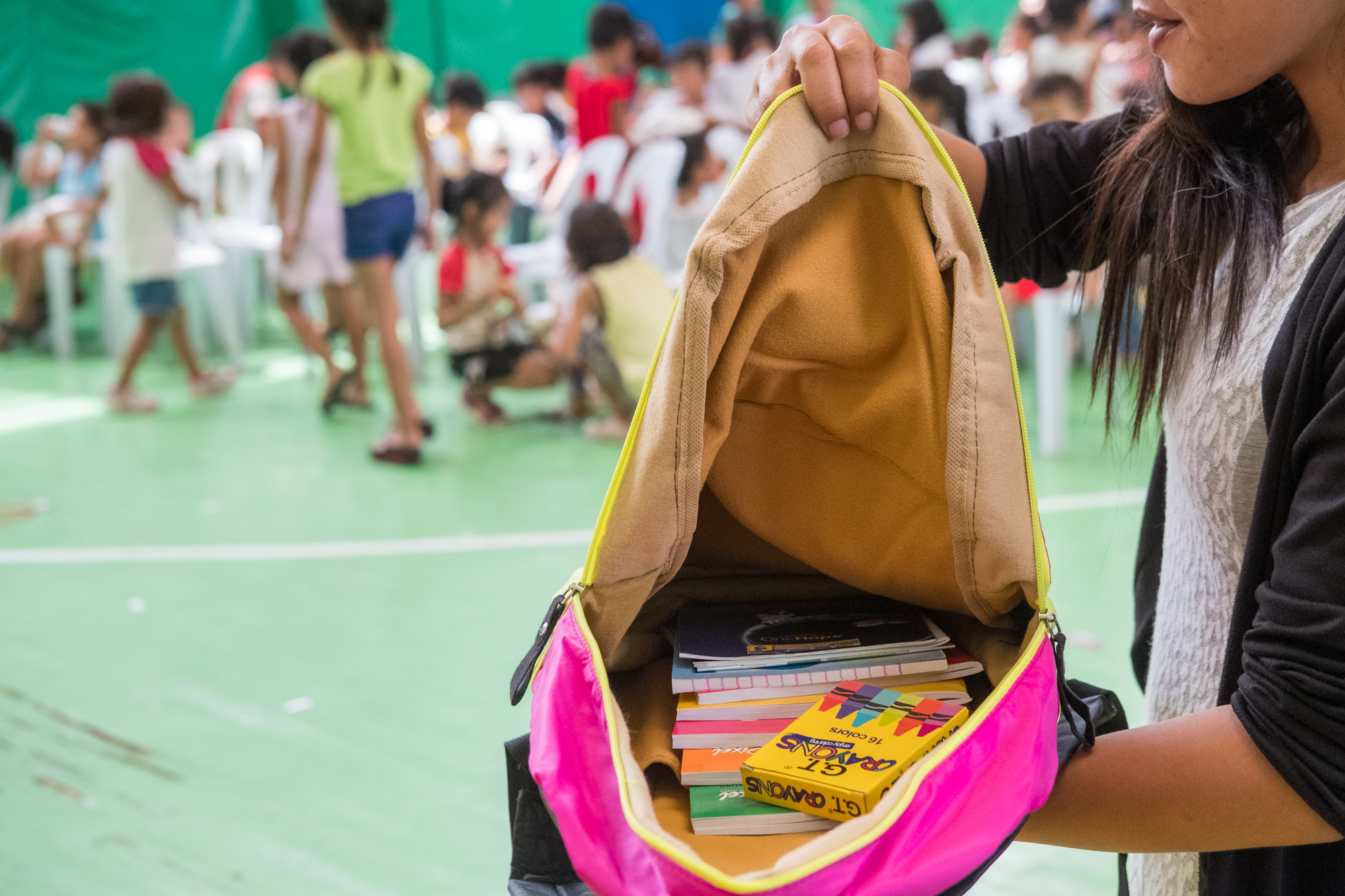  Rose Marie Plando (right) holds open a backpack filled with school supplies at a community-giving event in Cebu, Philippines. Frank works with organizations that donate the supplies. Sometimes he purchases the material himself. 