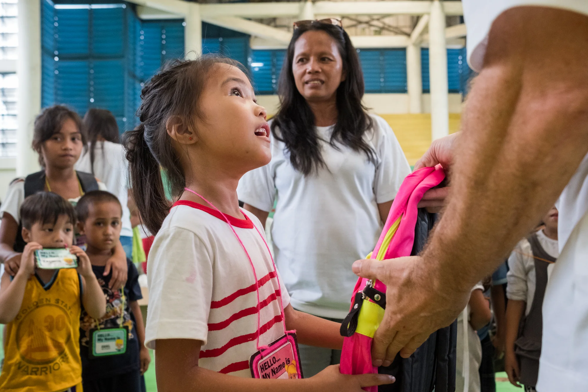 Frank Becker (off-camera right) distributes free backpacks filled with school supplies at a community-giving event in Cebu, Philippines.