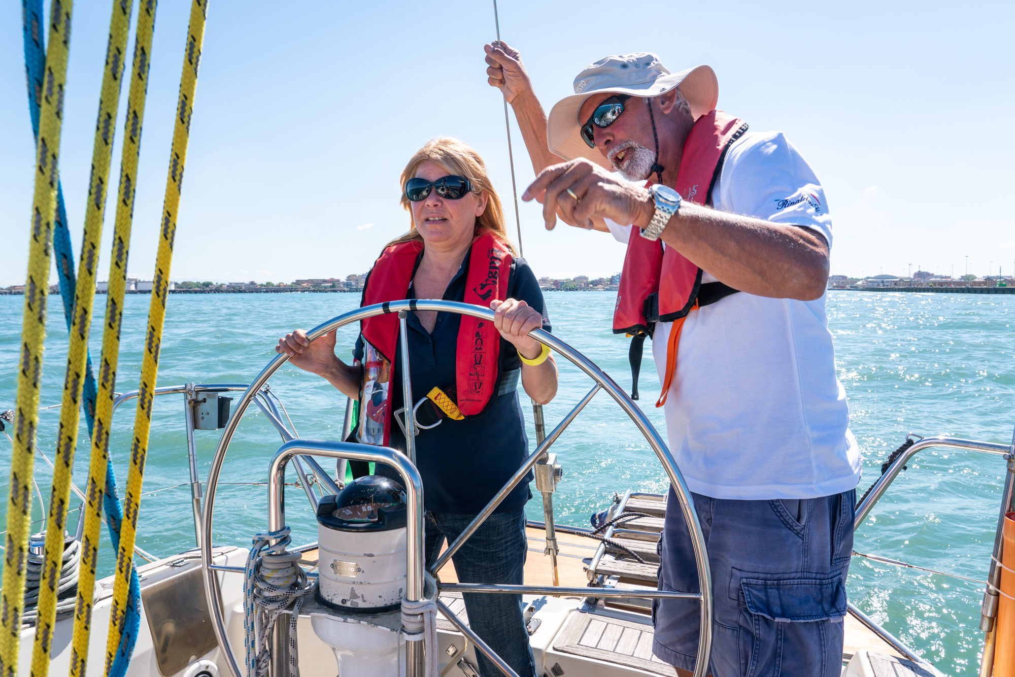  Patrizia Pilloni (left) steers the sailboat through Fiumicino Harbor in Italy as her instructor, Claudio Rinaldini, gives instruction. 