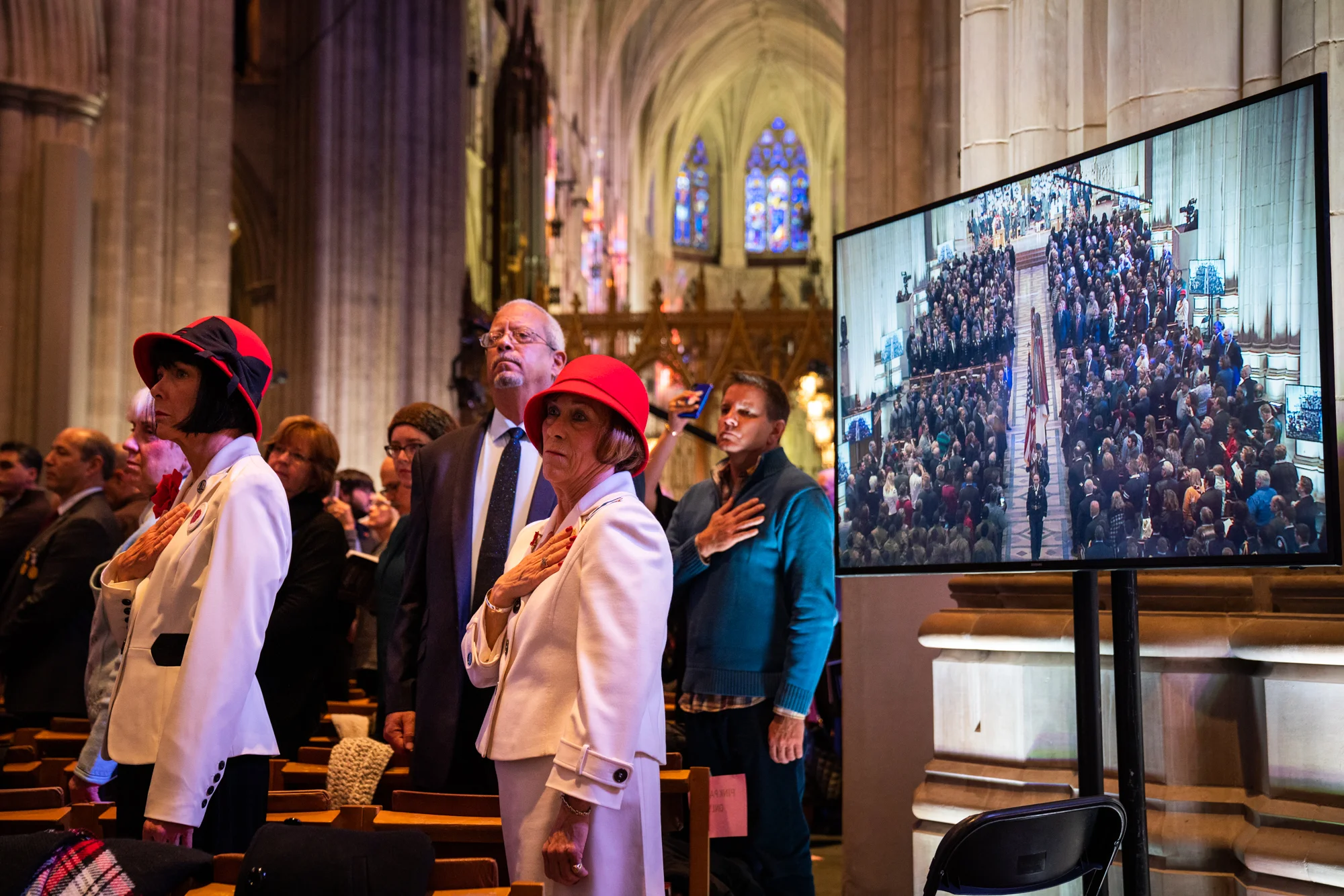 Attendees stand and acknowledge The National Anthem as the final procession passes through the cathedral.