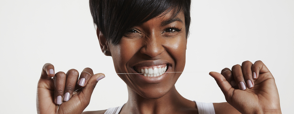 Beautiful woman flosses her healthy teeth