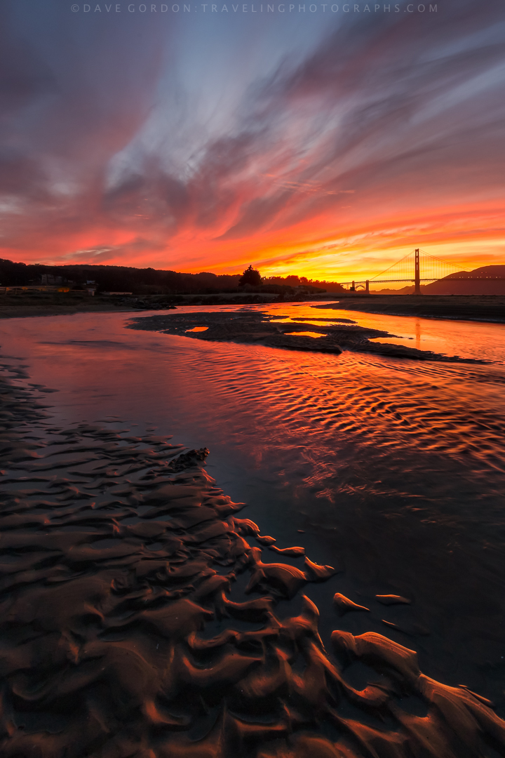 **Fire and Water**

Past sunset at Crissy Field—deep reds and oranges painting the sky, mud ripples with a stream reflecting the vibrant light like molten color, Golden Gate Bridge silhouetted in the background.

This is the magic that happens after 