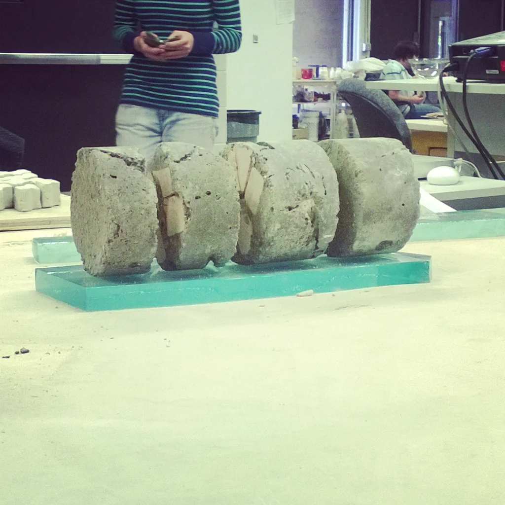 Ancient stone artifacts or columns displayed on a table in a laboratory or museum setting.
