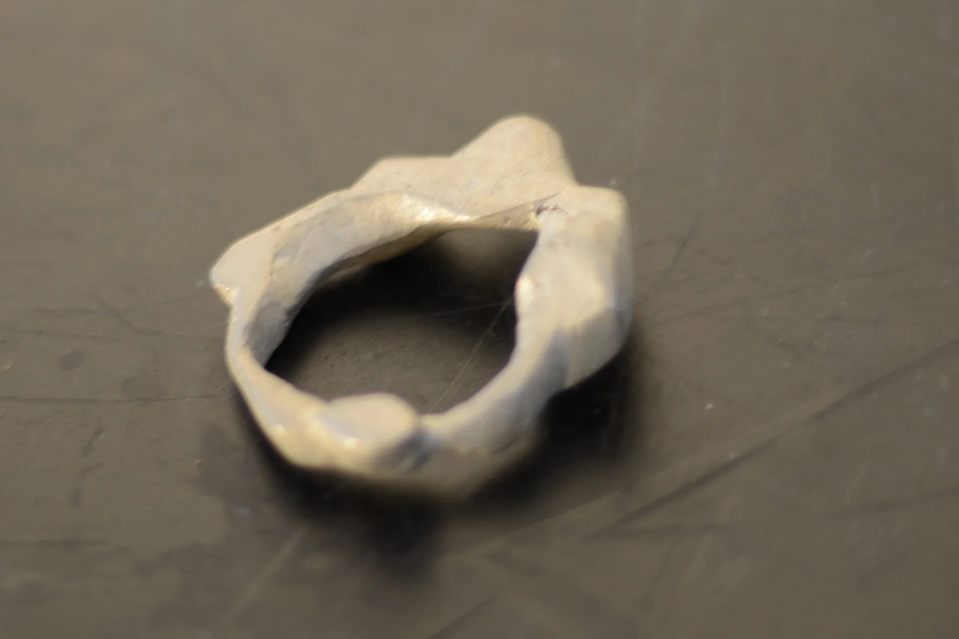 Close-up of a small, irregularly shaped, metallic object on a dark surface.