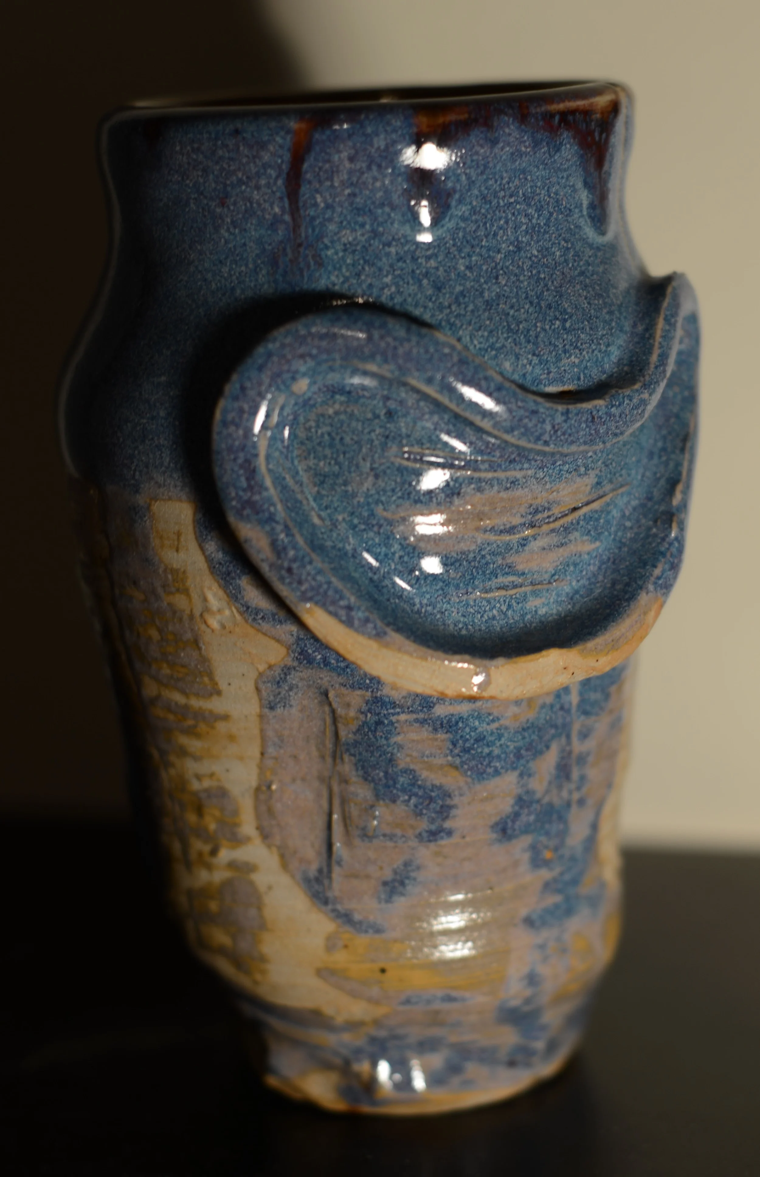 Close-up of a ceramic vase with a textured, multicolored blue and beige glaze.