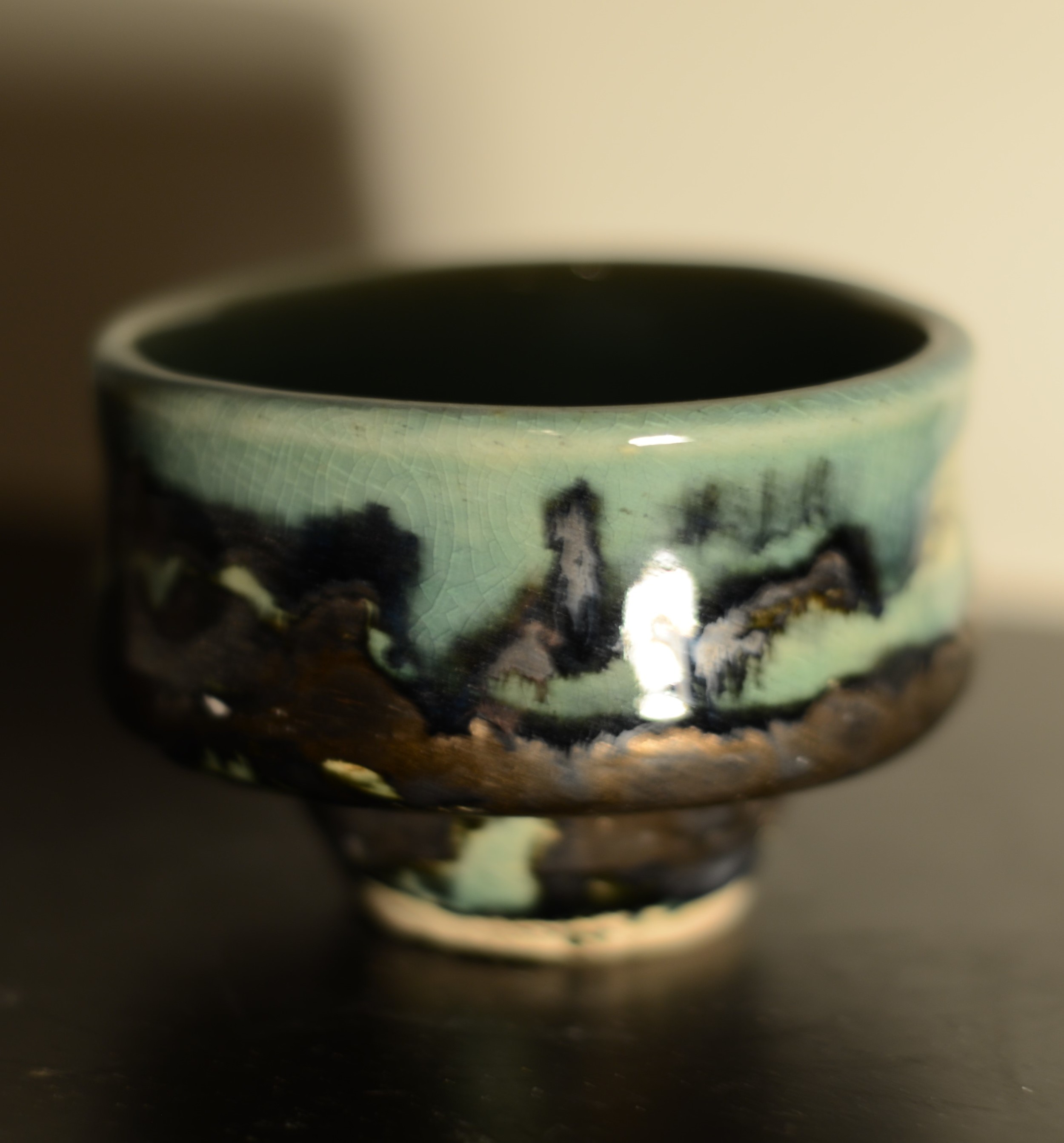 Close-up of a ceramic bowl with mountainous landscape design and a crackled glaze finish.