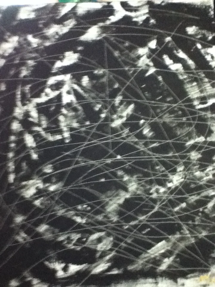 Close-up of a black surface with white scratches and streaks, possibly a damaged or scratched surface.