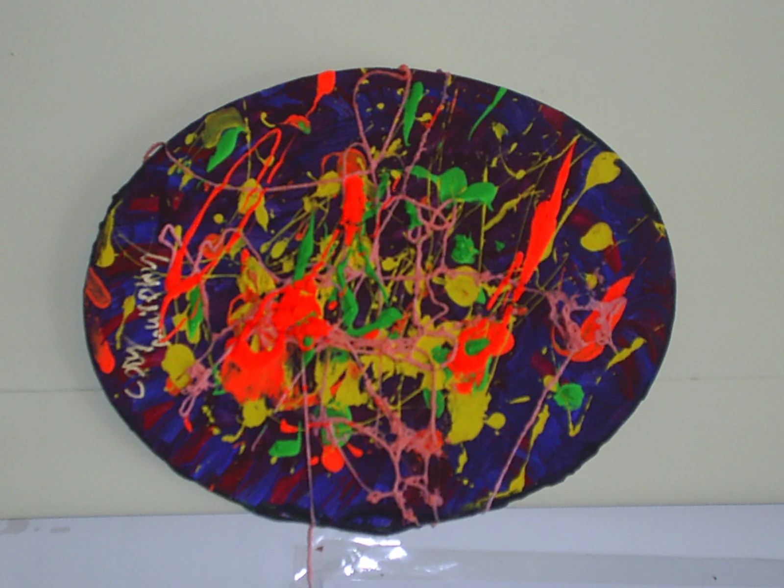 Colorful abstract paint splatter on a circular canvas.