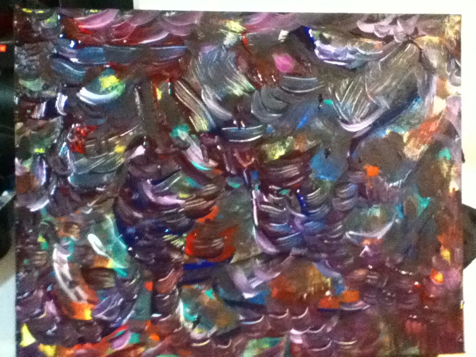 Close-up of an abstract painting with swirling, colorful metallic paint in shades of purple, blue, green, orange, and silver.