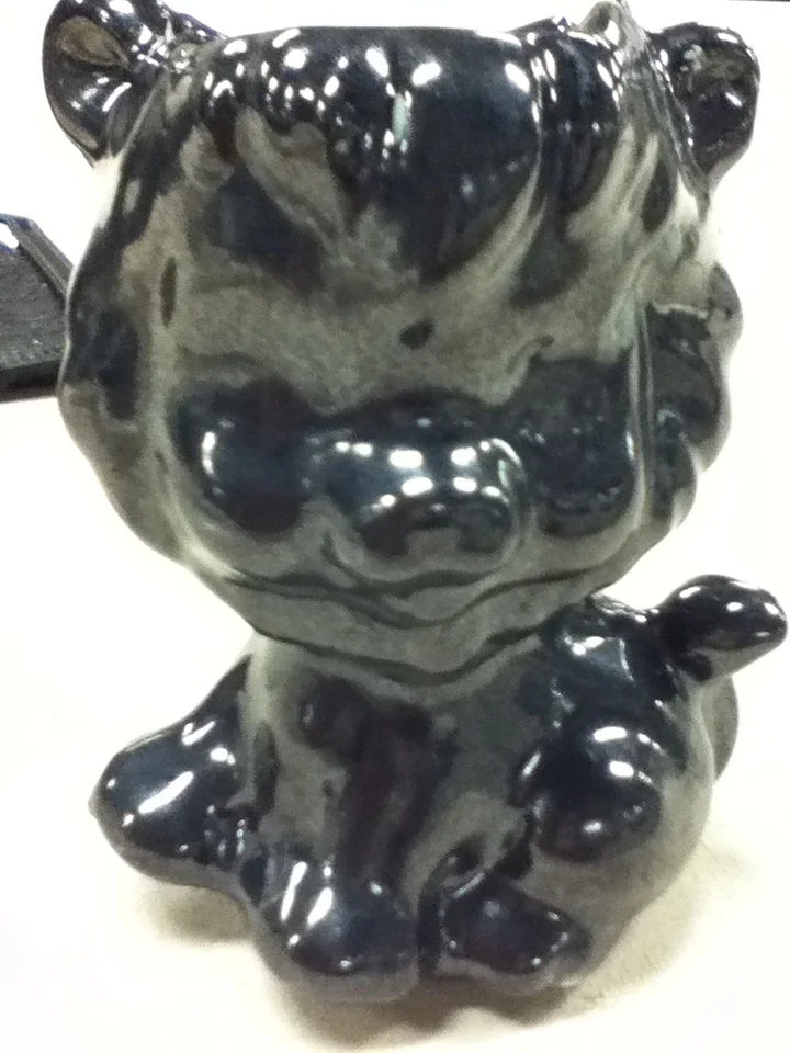Black and beige ceramic tiger figurine with a glossy finish.