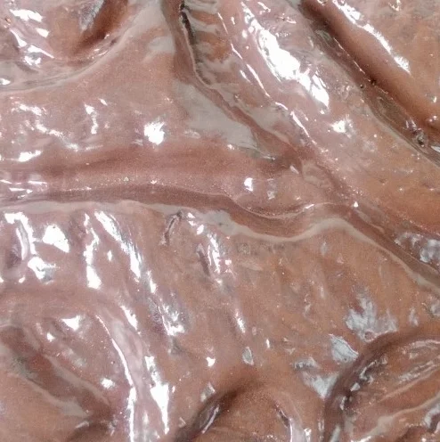 Close-up of melted chocolate with a shiny, wavy surface.