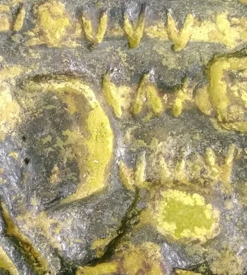 Close-up of a weathered surface with engraved yellowish lettering.