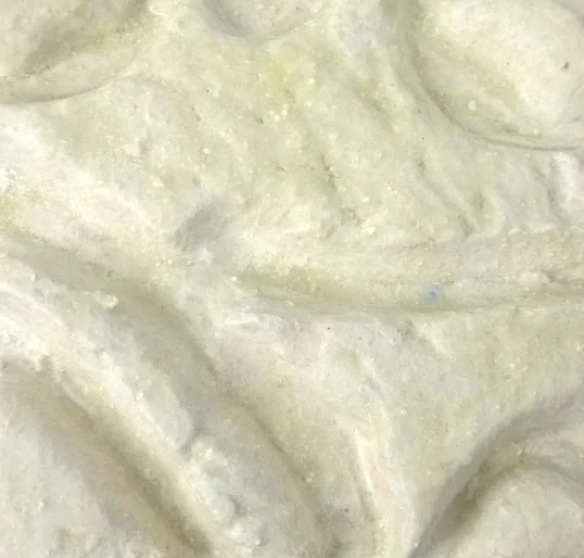 Close-up of a textured, light-colored substance, possibly a creamy food or cosmetic product.