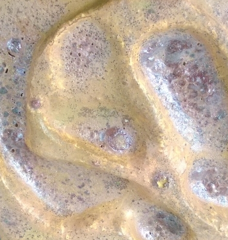 Close-up of a boiling, frothy, yellowish-brown liquid, possibly food or a bath.