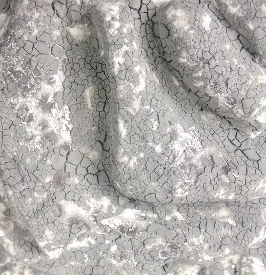 Close-up of cracked and peeling gray paint or surface with textured pattern.