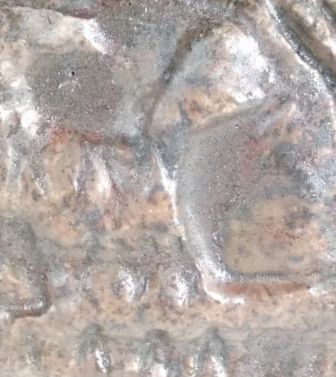 Close-up of a weathered and rusty metal surface with embossed or engraved text.