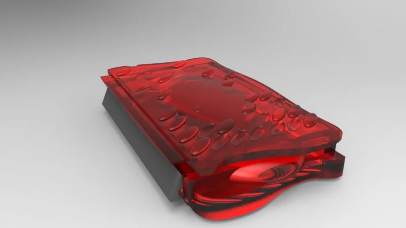 Close-up of a red, transparent, or glassy object resembling a smartphone or electronic device with water droplets on its surface, lying on a flat surface.