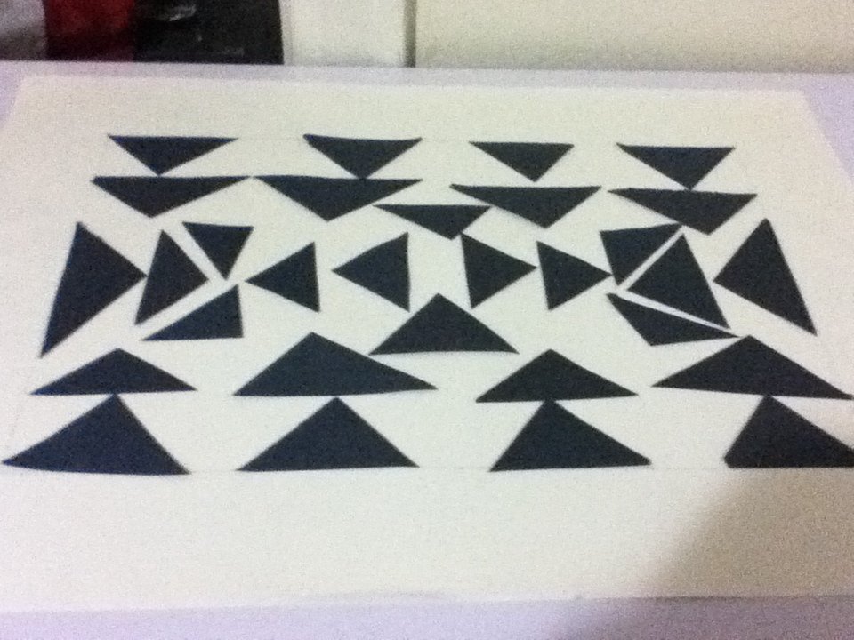 A white sheet with numerous black triangles arranged in a pattern.