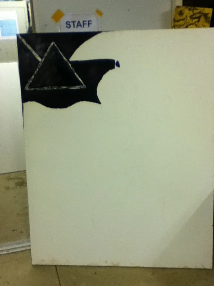 Painted black bat with a triangle in the middle on white background.