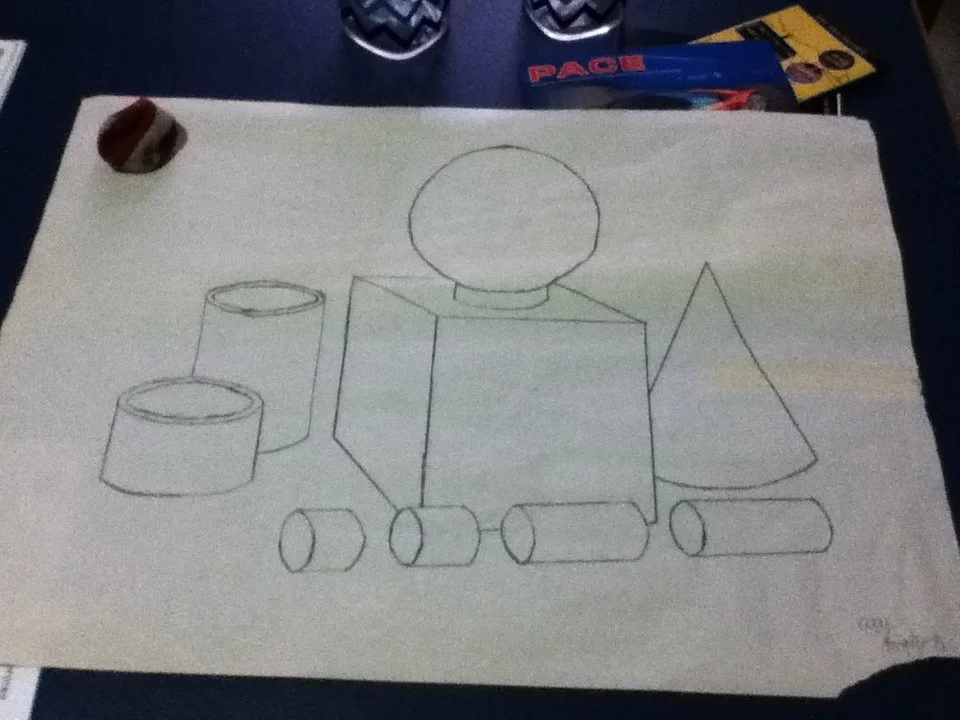 A drawing of geometric shapes including cylinders, a cube, a cone, and a sphere on a sheet of paper.