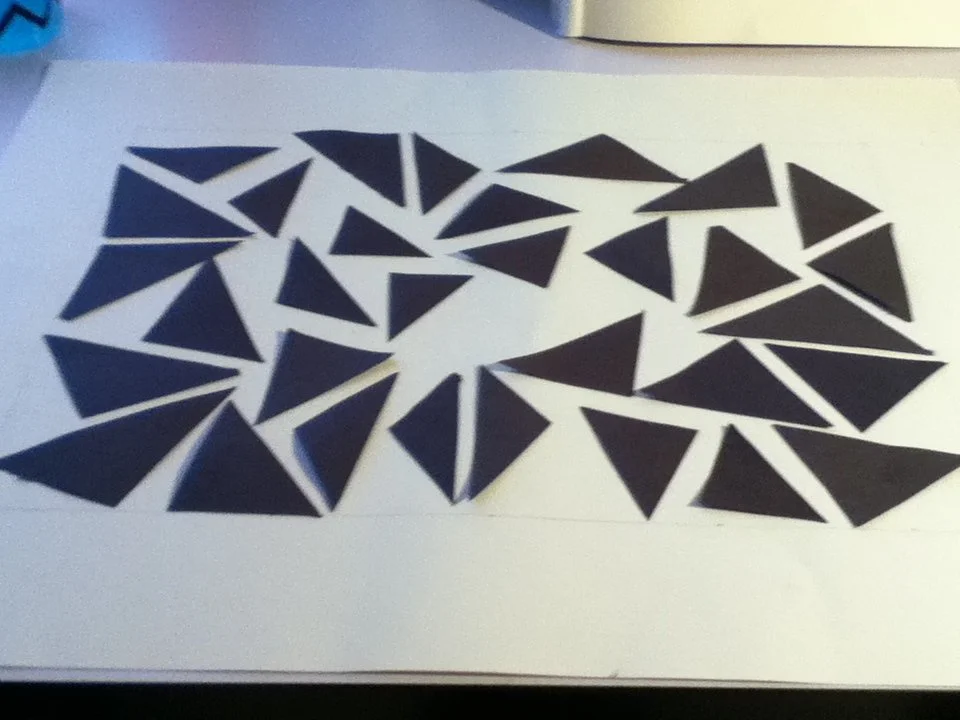 A white sheet of paper with numerous black triangles arranged in a heart shape.