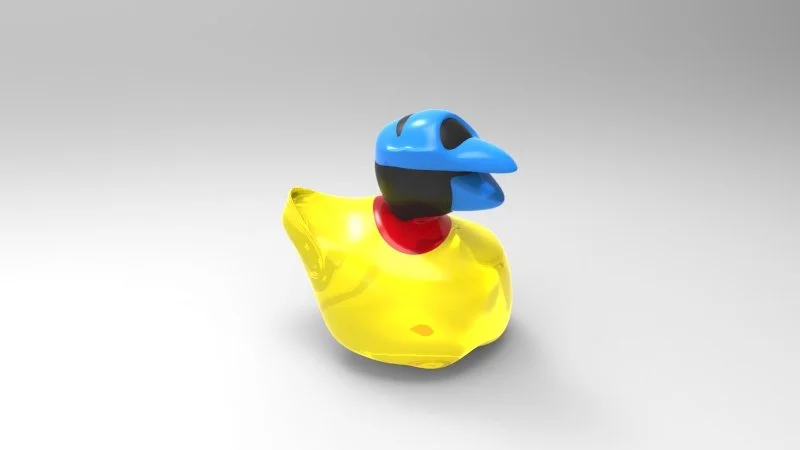 A rubber duck with a blue beak and a black eye, wearing a blue mask and a red collar, set against a plain gray background.